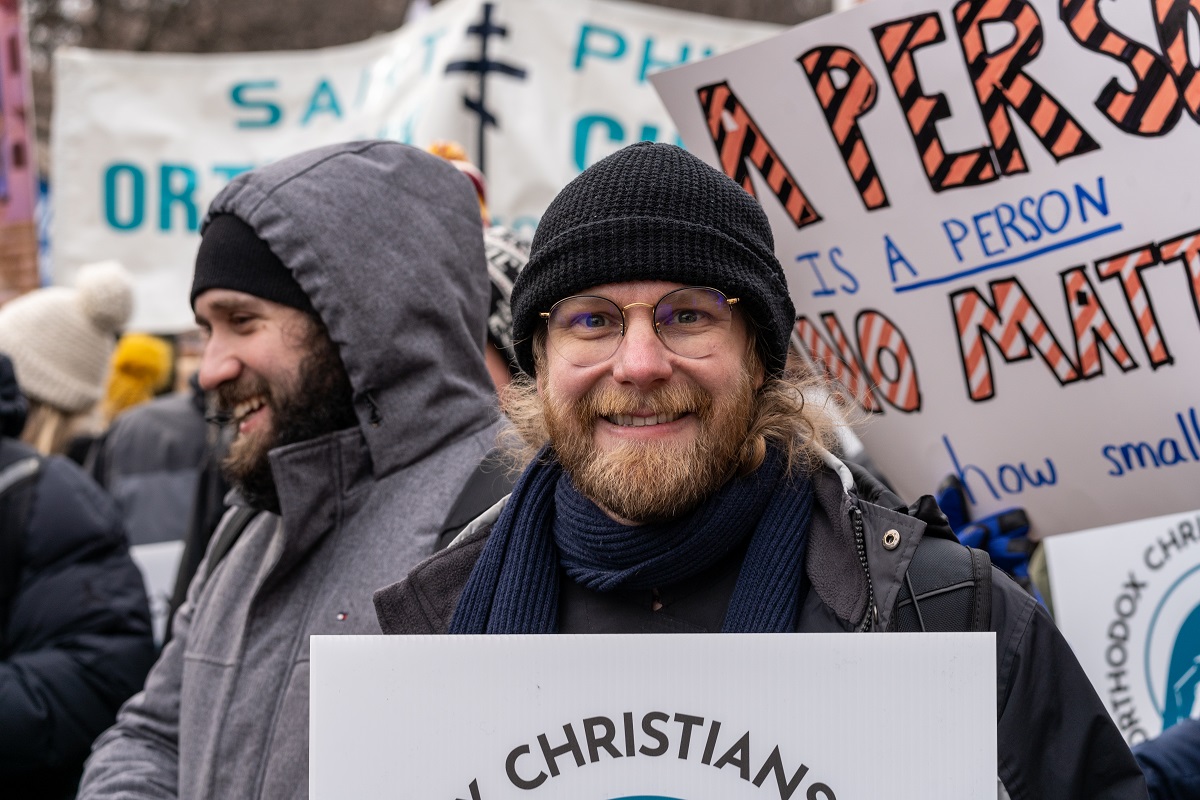 Seminarian smiles and holds up sign