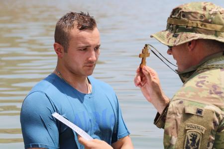 Fr James raises the cross before a soldier being baptized in the Gulf of Aden