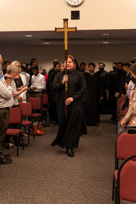 A seminarian leads the commencement procession holding up the cross